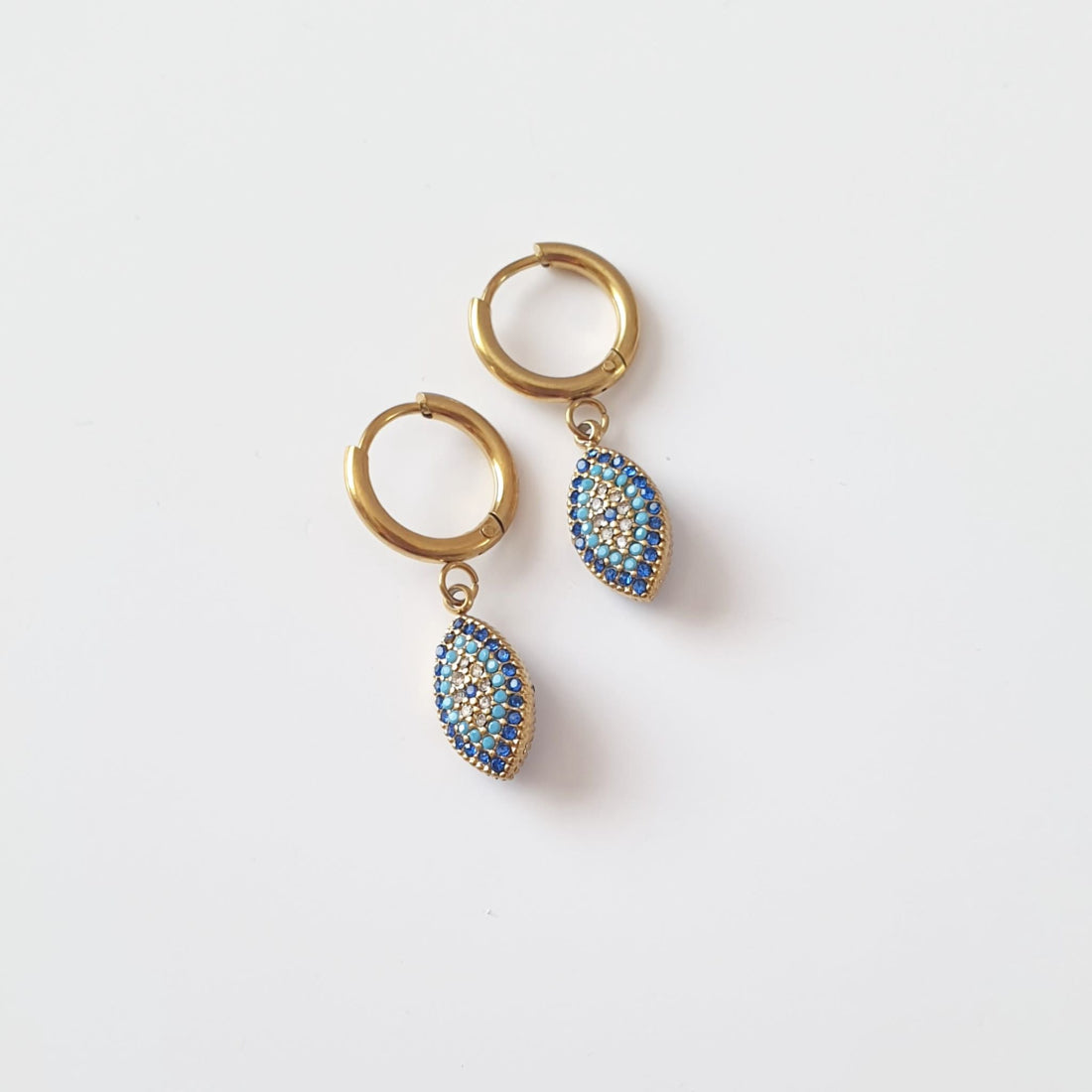 Χρυσοί ατσάλινοι κρίκοι με κρεμαστό μάτι από μπλε ζιργκόν σε σχήμα ματιού.